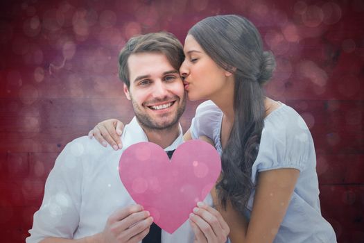 Pretty brunette giving boyfriend a kiss and her heart against blue abstract light spot design