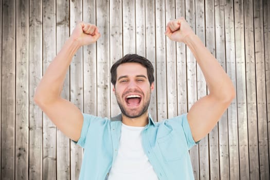 Happy casual man cheering at camera against wooden planks background