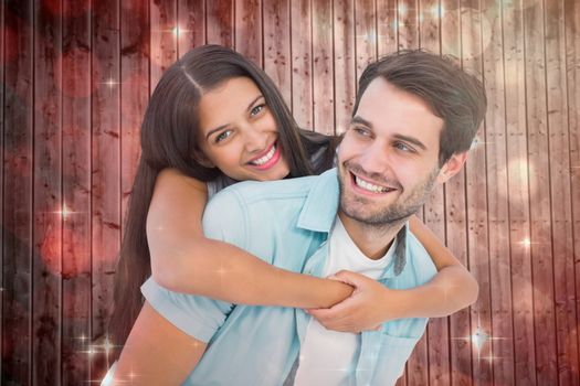 Happy casual man giving pretty girlfriend piggy back against light design shimmering on red