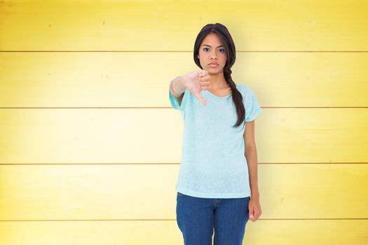 Disappointed brunette giving thumbs down against wooden planks