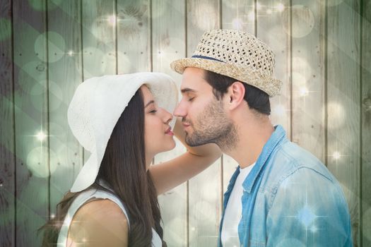 Happy hipster couple about to kiss against light design shimmering on green
