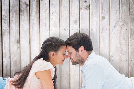 Attractive young couple smiling at each other against wooden planks
