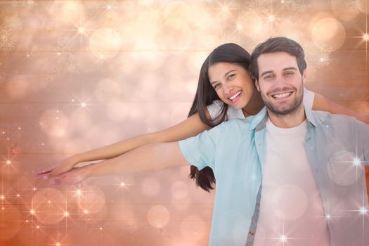 Happy casual man giving pretty girlfriend piggy back against shimmering light design on red