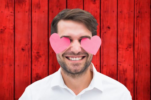 Handsome man with hearts over his eyes against wooden background in red