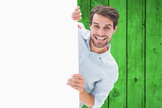 Attractive young man smiling and holding poster against bright green wooden planks