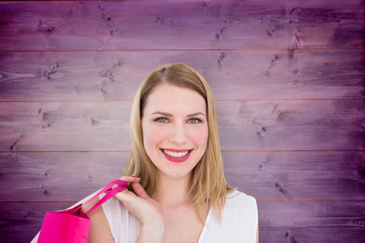 Portrait of a smiling blonde woman holding shopping bag against wooden planks background