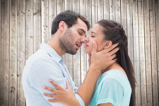 Attractive young couple about to kiss against wooden planks background