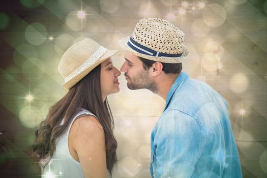 Happy hipster couple about to kiss against light design shimmering on green