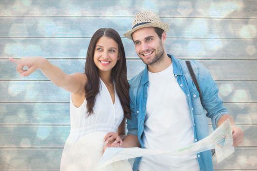 Happy hipster couple looking at map against light glowing dots design pattern