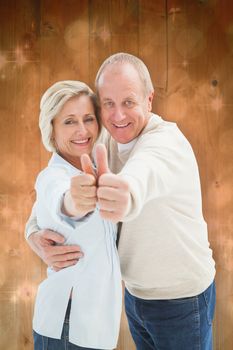 Happy mature couple showing thumbs up against light design shimmering on green