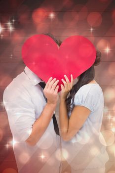 Couple covering their kiss with a heart against light design shimmering on red