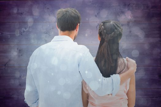 Attractive young couple standing and looking against blue abstract light spot design