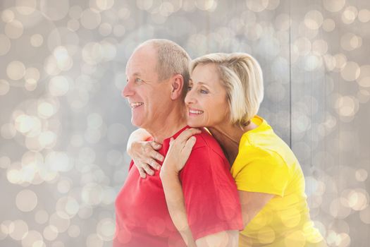 Happy mature couple hugging and smiling against light glowing dots design pattern