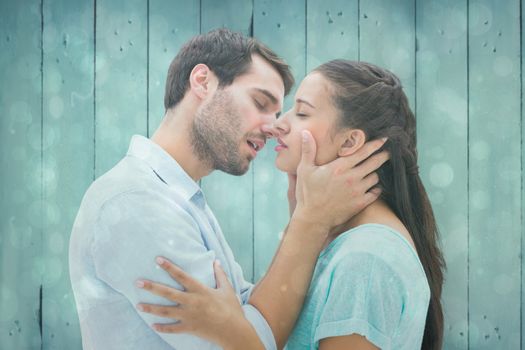 Attractive young couple about to kiss against blue abstract light spot design