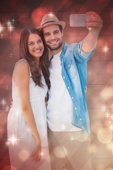 Happy hipster couple taking a selfie against light design shimmering on red