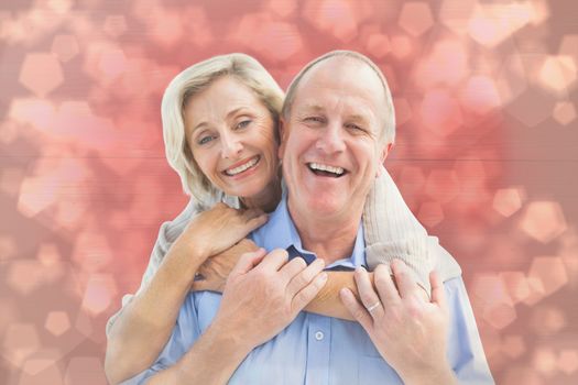 Happy mature couple embracing smiling at camera against light glowing dots design pattern