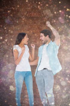 Happy casual couple cheering together against white snow and stars on black