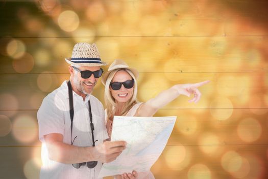 Happy tourist couple using map and pointing against light circles on black background