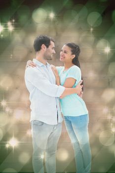 Attractive young couple hugging each other against light design shimmering on green