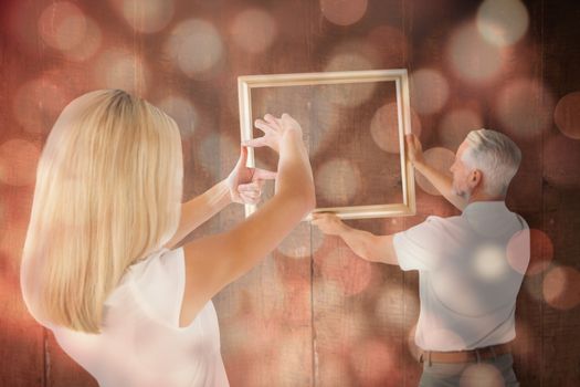Couple hanging a frame together against light circles on black background