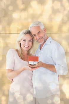 Happy couple holding miniature model house against light glowing dots design pattern