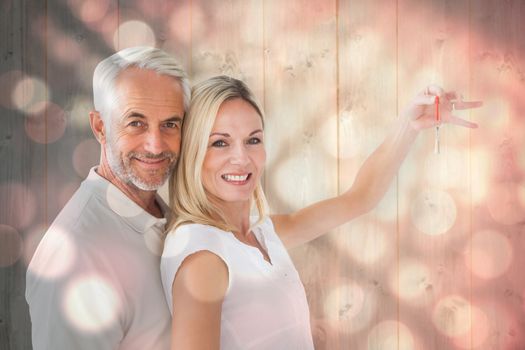 Happy couple showing their new house key against light circles on black background