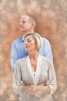 Happy mature couple embracing with eyes closed against light glowing dots design pattern