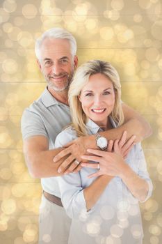 Happy couple smiling at camera and embracing against light glowing dots design pattern
