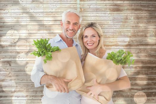 Happy couple carrying paper grocery bags against light circles on bright background