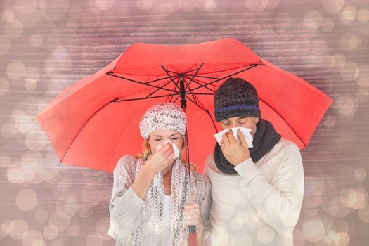 Couple in winter fashion sneezing under umbrella against light glowing dots design pattern