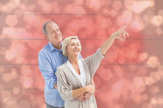 Happy mature couple embracing and looking against light glowing dots design pattern
