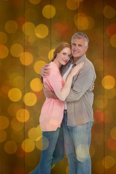 Casual couple hugging and smiling against close up of christmas lights