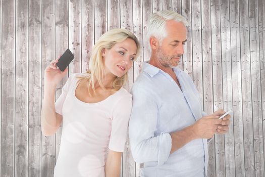 Happy couple texting on their smartphones against light circles on grey background