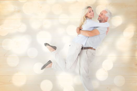 Man picking up his partner while hugging here against light circles on grey background