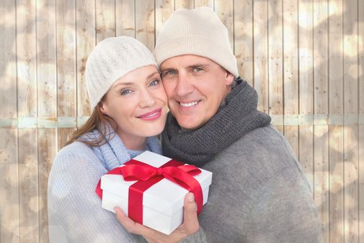 Casual couple in warm clothing holding gift against light glowing dots design pattern