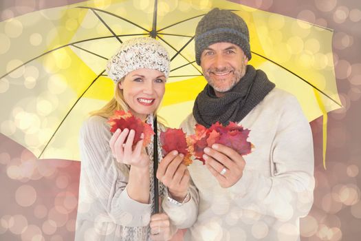 Couple in winter fashion showing autumn leaves under umbrella against light glowing dots design pattern