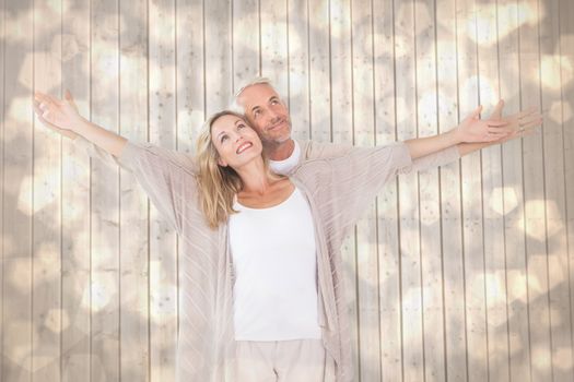 Happy couple standing with arms outstretched against light glowing dots design pattern