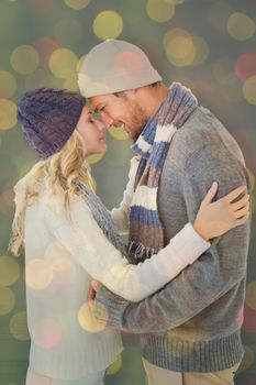 Attractive couple in winter fashion hugging against close up of christmas lights