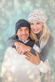 Happy couple in winter fashion embracing against light glowing dots design pattern