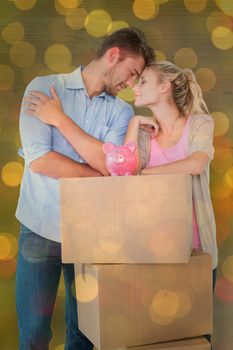 Attractive young couple leaning on boxes with piggy bank against close up of christmas lights