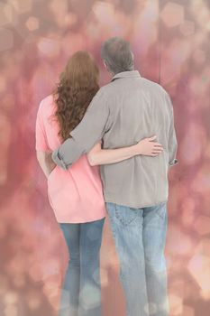 Casual couple standing arms around against light glowing dots design pattern