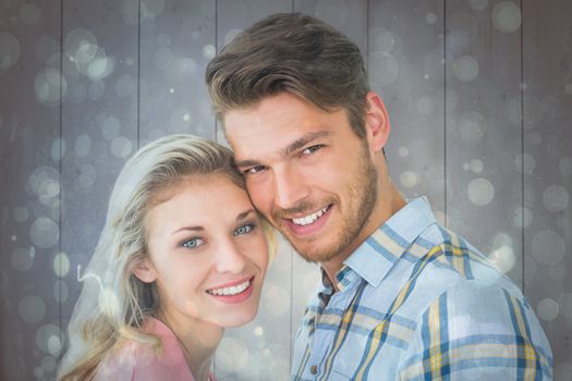 Attractive couple smiling at camera against blue abstract light spot design