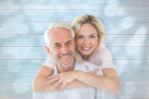 Smiling couple embracing and looking at camera against light circles on grey background