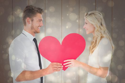 Attractive young couple holding red heart against black abstract light spot design