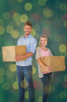 Attractive young couple carrying moving boxes against close up of christmas lights