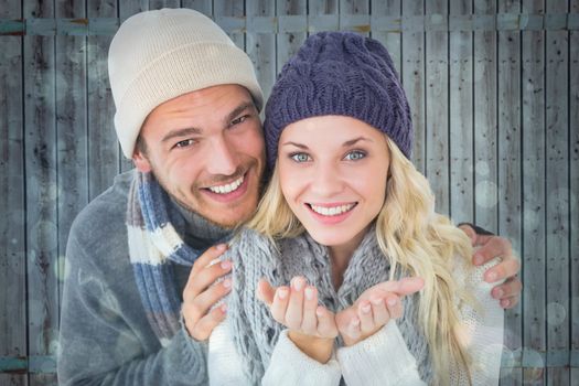 Attractive couple in winter fashion smiling at camera against blue abstract light spot design