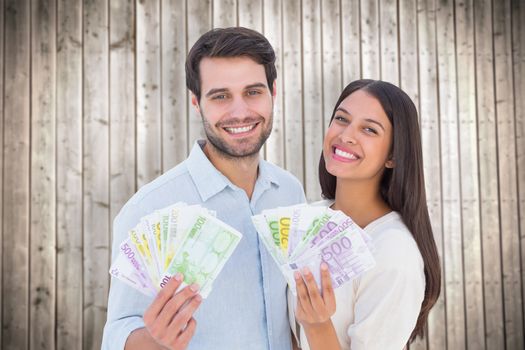 Happy couple showing their money against wooden planks background