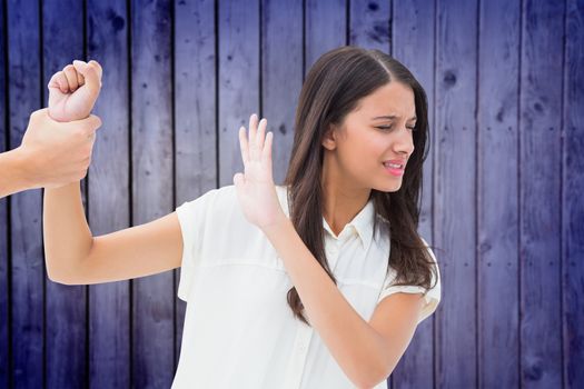 Fearful brunette being grabbed by the hand against wooden planks background