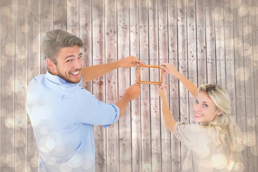 Attractive young couple hanging a frame against light glowing dots design pattern