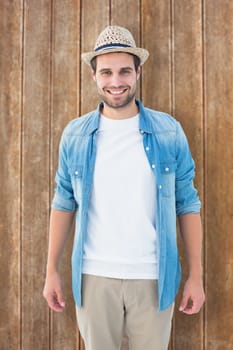 Handsome hipster smiling at camera against wooden planks background